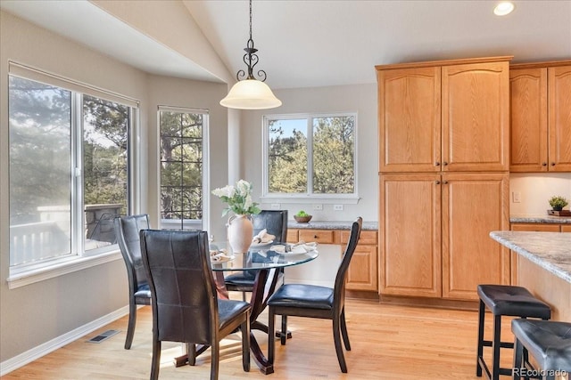 dining space featuring light wood-style floors, lofted ceiling, a wealth of natural light, and visible vents