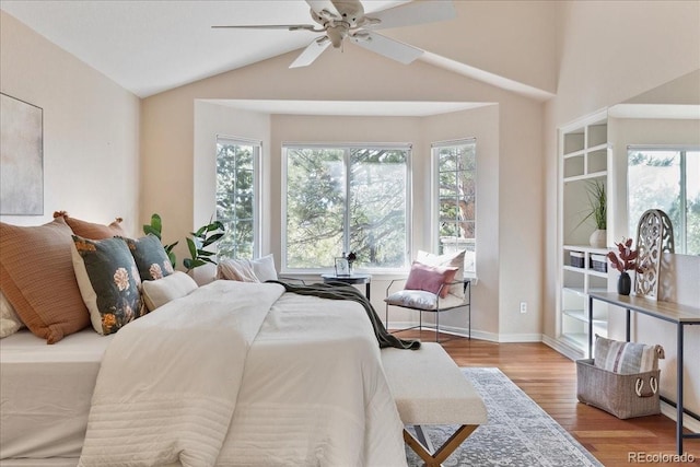 bedroom with multiple windows, vaulted ceiling, baseboards, and wood finished floors