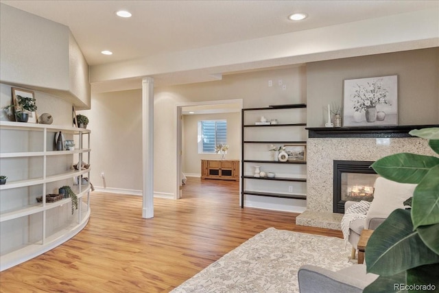 living room featuring recessed lighting, baseboards, a premium fireplace, and wood finished floors