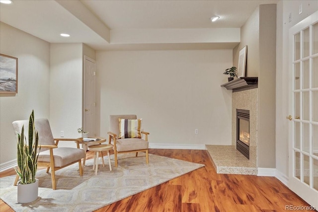 living area featuring a glass covered fireplace, baseboards, and wood finished floors