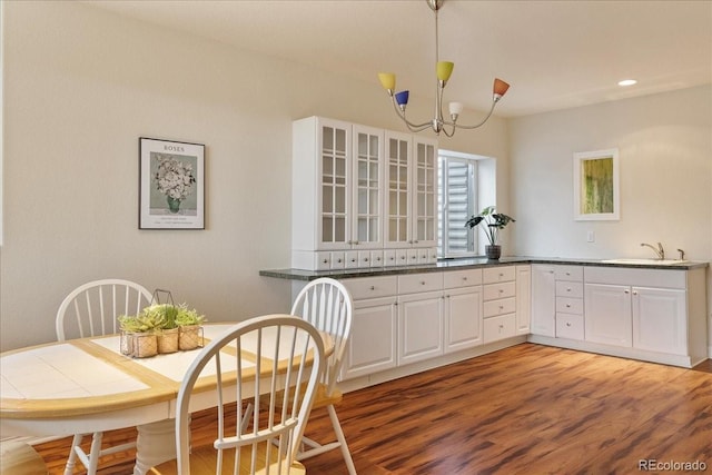 kitchen featuring hanging light fixtures, light wood-type flooring, glass insert cabinets, and white cabinets