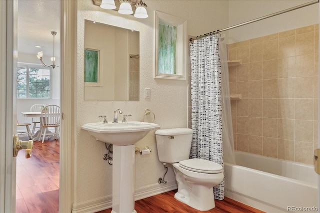 full bath featuring a textured wall, toilet, shower / bath combo with shower curtain, wood finished floors, and a chandelier