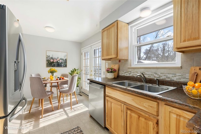 kitchen with appliances with stainless steel finishes, backsplash, light brown cabinetry, and sink