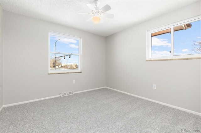 carpeted spare room with ceiling fan and a textured ceiling