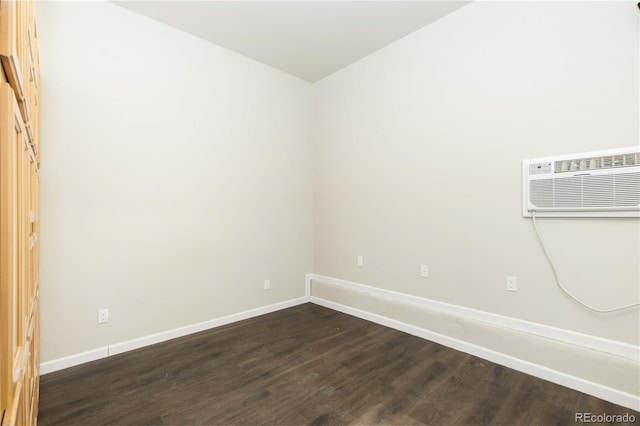 empty room featuring dark hardwood / wood-style flooring and an AC wall unit