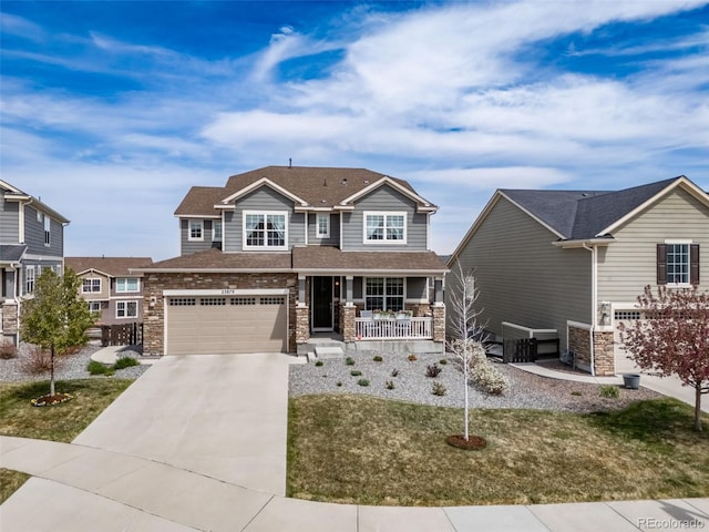 craftsman-style home with a porch, driveway, a front lawn, an attached garage, and stone siding