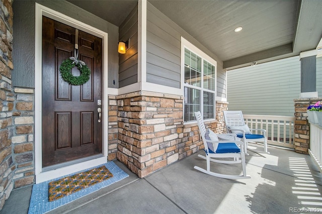 doorway to property featuring covered porch and stone siding