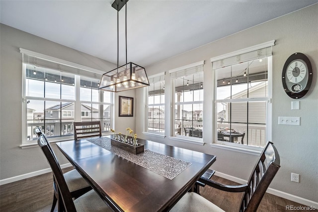 dining area featuring baseboards, dark wood-type flooring, and a chandelier