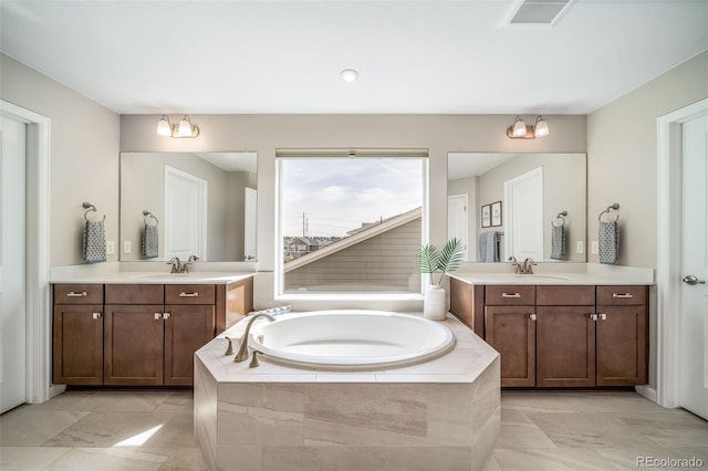 bathroom with visible vents, a sink, a bath, and two vanities