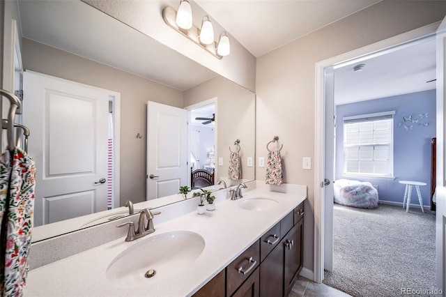 ensuite bathroom featuring double vanity, a sink, connected bathroom, and baseboards