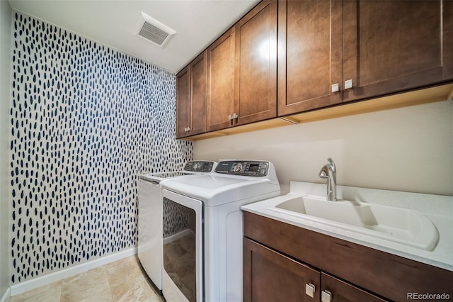 washroom with visible vents, washing machine and dryer, baseboards, a sink, and cabinet space