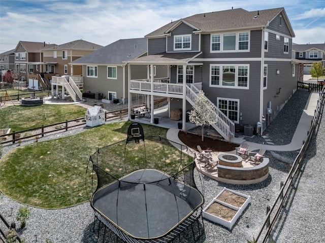 back of house with stairs, a trampoline, an outdoor fire pit, and a patio area