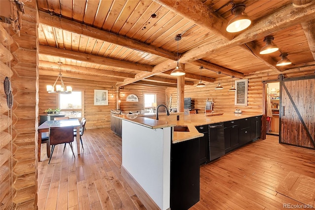 kitchen with a barn door, sink, pendant lighting, and light hardwood / wood-style floors