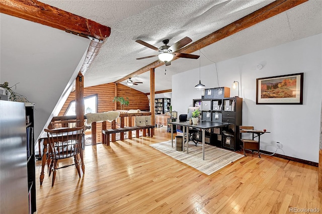 dining room featuring hardwood / wood-style flooring, ceiling fan, vaulted ceiling with beams, a textured ceiling, and log walls