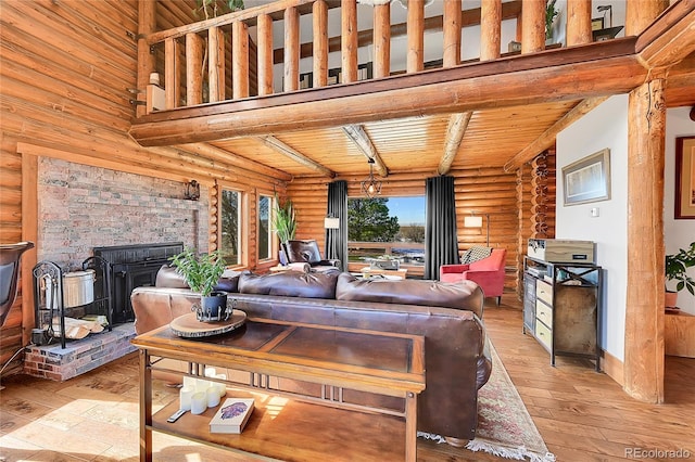 living room with a towering ceiling, light hardwood / wood-style floors, a wood stove, and wooden ceiling