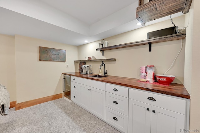 bar with butcher block counters, sink, light carpet, and white cabinets