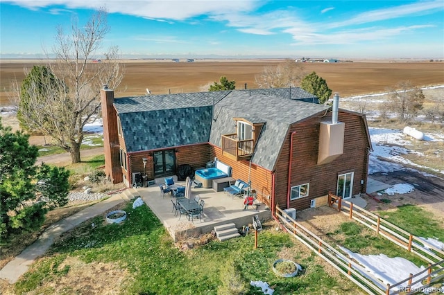 rear view of house with a rural view, a patio area, and a balcony