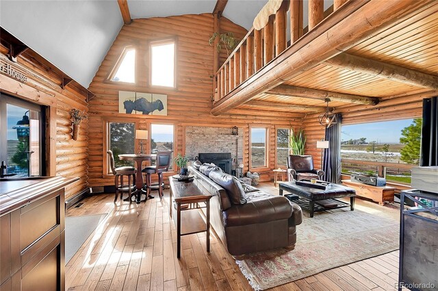 48155 E 56th Ave, Bennett, CO 80102 - living room featuring hardwood / wood-style floors, beamed ceiling, log walls, a fireplace, and high vaulted ceiling