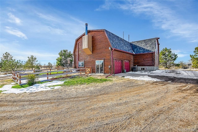 48155 E 56th Ave, Bennett, CO 80102 - view of side of home with a gambrel roof, a shingled roof, and an attached garage