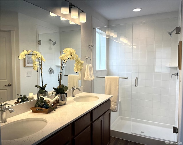 full bath featuring a sink, double vanity, a stall shower, and recessed lighting