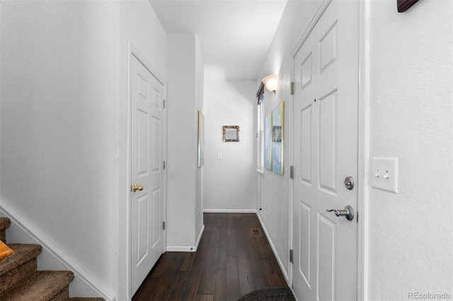 hall featuring baseboards, dark wood finished floors, and stairs