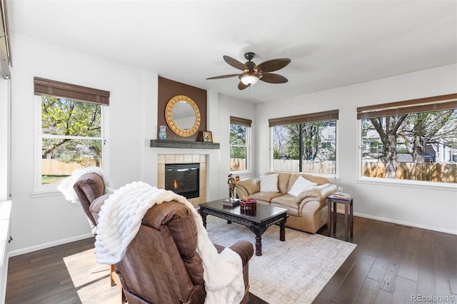 living room featuring baseboards, a ceiling fan, and a wealth of natural light