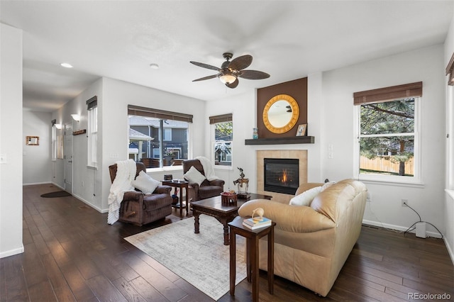 living room featuring plenty of natural light, ceiling fan, dark wood finished floors, and a tile fireplace