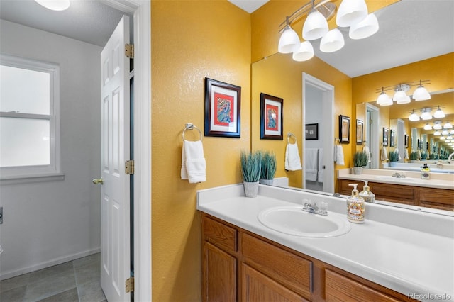 bathroom with tile patterned floors, a notable chandelier, and vanity