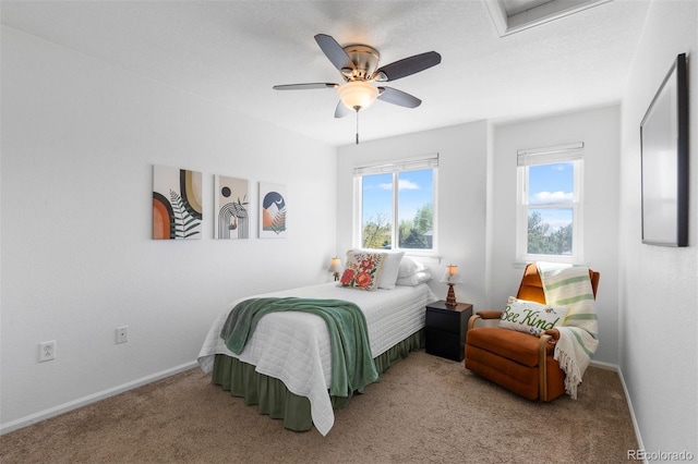 bedroom with baseboards, ceiling fan, attic access, and light colored carpet