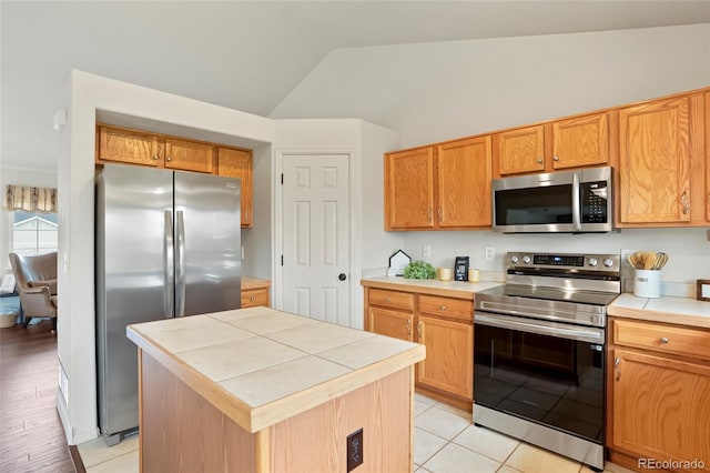 4873 Eckert St, Castle Rock, CO 80104 - kitchen featuring stainless steel appliances, lofted ceiling, tile countertops, a center island, and light tile patterned floors