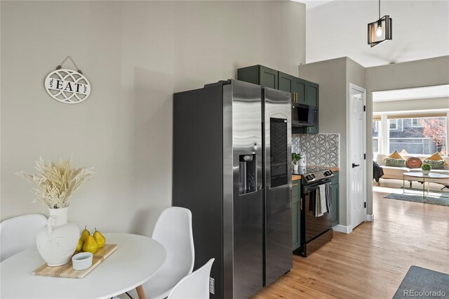 5965 Corinth Dr, Colorado Springs, CO 80923 - kitchen with stainless steel fridge, black range with electric cooktop, light wood-type flooring, decorative backsplash, and a towering ceiling