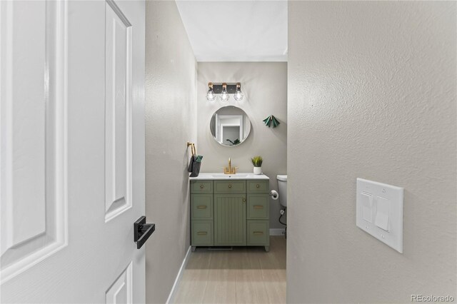 5965 Corinth Dr, Colorado Springs, CO 80923 - half bathroom featuring wood finished floors, vanity, baseboards, and toilet