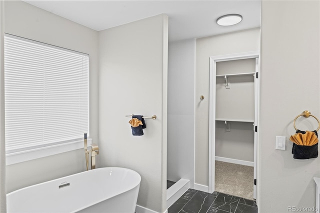 5965 Corinth Dr, Colorado Springs, CO 80923 - full bathroom featuring a soaking tub, marble look tiles, baseboards, a stall shower, and a walk in closet