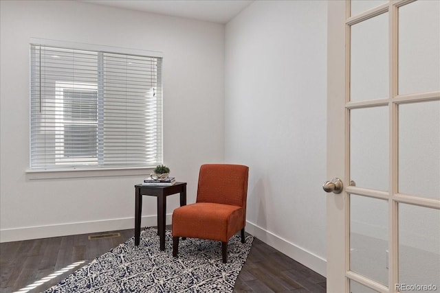 living area with dark wood finished floors, visible vents, and baseboards