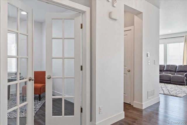 corridor with visible vents, french doors, baseboards, and wood finished floors