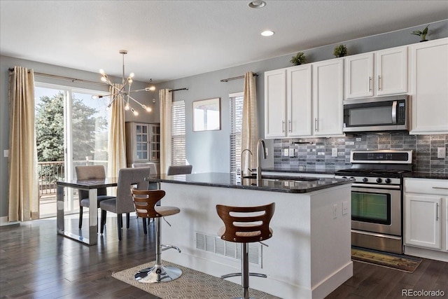 kitchen featuring decorative backsplash, dark wood-type flooring, appliances with stainless steel finishes, and a sink