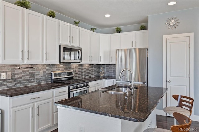 kitchen featuring tasteful backsplash, white cabinets, appliances with stainless steel finishes, and a sink