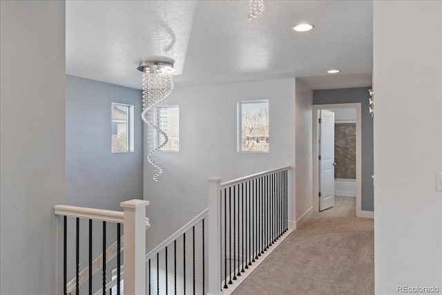 corridor with baseboards, carpet, an upstairs landing, recessed lighting, and a textured ceiling