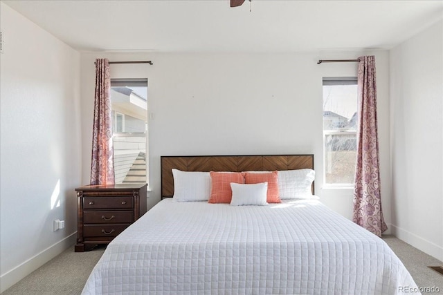 carpeted bedroom with visible vents, a ceiling fan, and baseboards