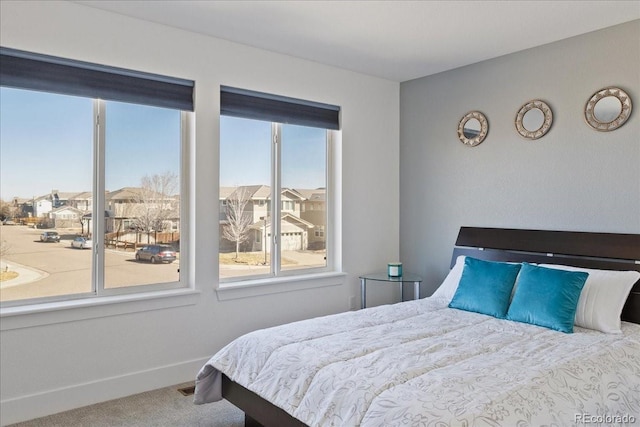 bedroom with a residential view, baseboards, and carpet