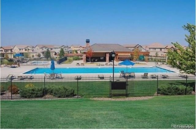 pool with a yard, a residential view, and fence