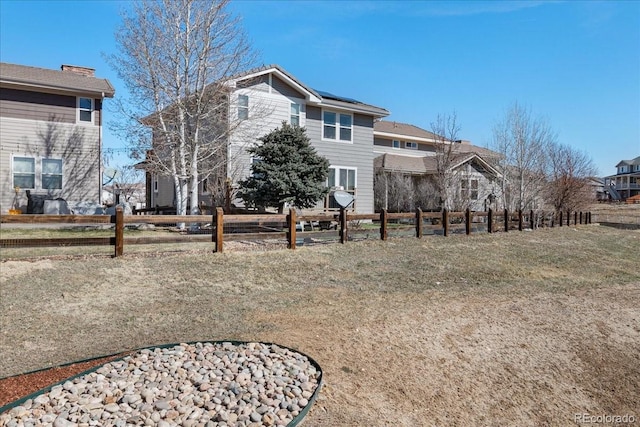 exterior space with a lawn, solar panels, and fence