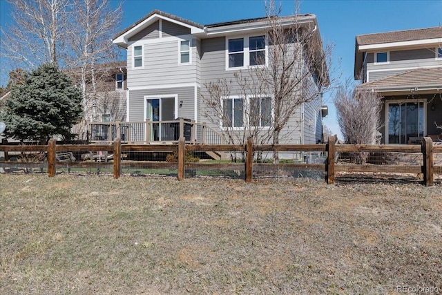 rear view of house with a yard, fence, and a wooden deck