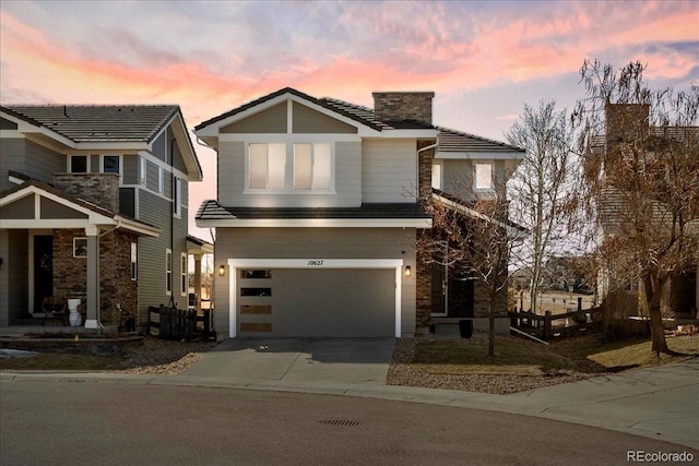 view of front facade with a garage, a chimney, and driveway