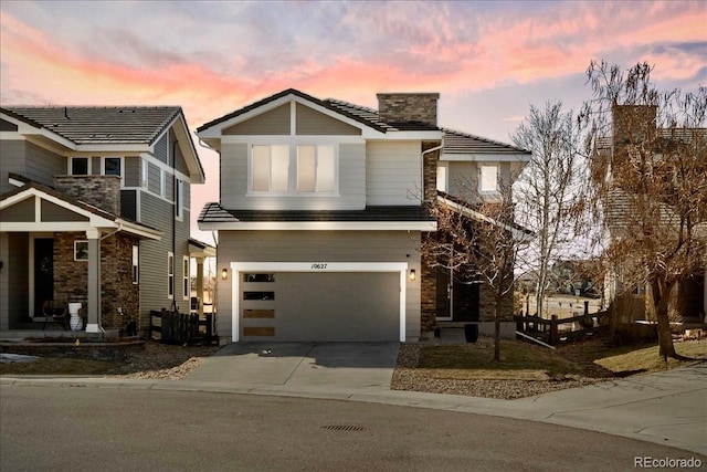 view of front of home featuring driveway, a chimney, and a garage