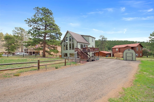 view of front of property featuring a storage unit, an outdoor structure, a deck, stairway, and driveway