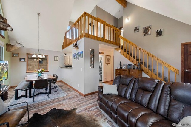 living room with wood finished floors, high vaulted ceiling, stairs, a chandelier, and baseboards