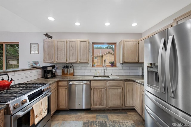 kitchen featuring appliances with stainless steel finishes, a sink, decorative backsplash, dark countertops, and recessed lighting