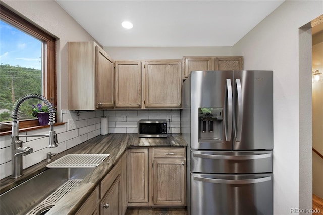 kitchen with stainless steel appliances, a sink, decorative backsplash, recessed lighting, and light brown cabinets