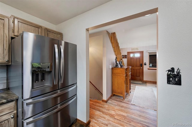 kitchen featuring stainless steel fridge, light wood-type flooring, baseboards, and dark countertops